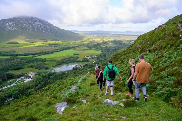 Students walking in a line down a steep green hill.